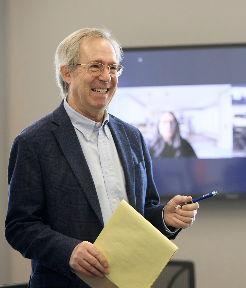 Martin Teaching. He's holding a pad and there's a screen behind him.